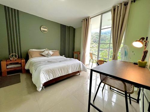 a bedroom with a bed and a table and a window at Montes De Beraka in Minca