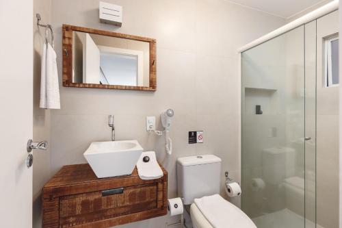 a bathroom with a sink and a toilet and a mirror at Pousada Bora Bora in Bombinhas