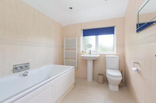 a bathroom with a tub and a toilet and a sink at Charles Alexander Short Stay - Moorway House in Poulton le Fylde