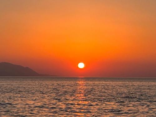 a sunset over the ocean with the sun setting at Elisa Seaside Luxury Suite in Loutraki