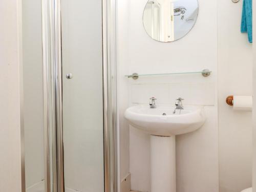 a white bathroom with a sink and a mirror at Archers in Keswick