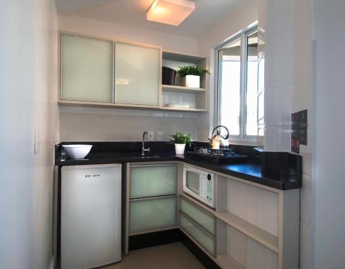 a kitchen with a sink and a microwave at Pousada Bora Bora in Bombinhas