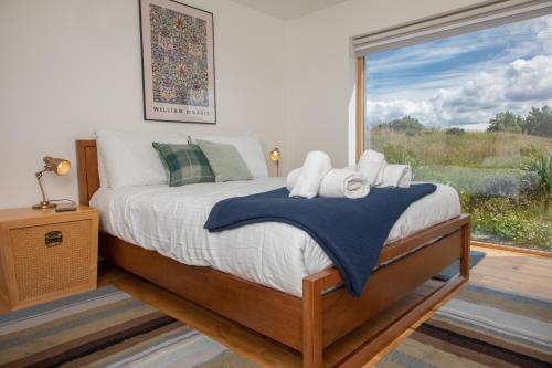 ein Schlafzimmer mit einem Bett und einem großen Fenster in der Unterkunft Cuillrigh - Luxury house, loch & mountain views in Portree