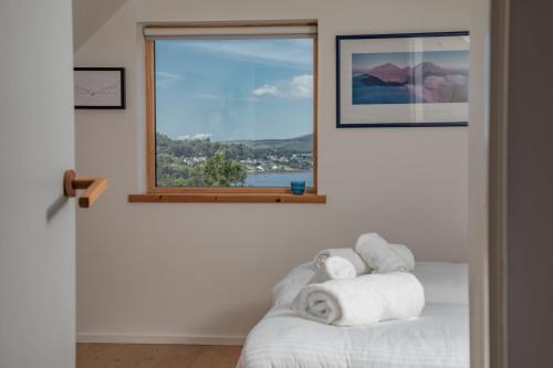 1 dormitorio con ventana y toallas en una cama en Cuillrigh - Luxury house, loch & mountain views, en Portree