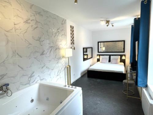 La salle de bains est pourvue d'une baignoire et d'un lit. dans l'établissement Le Vauban, à Mulhouse