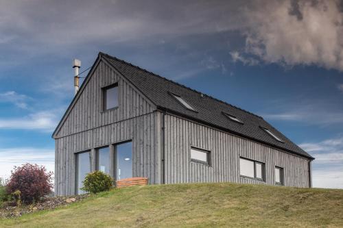 a gray house on top of a hill at Cuillrigh - Luxury house, loch & mountain views in Portree