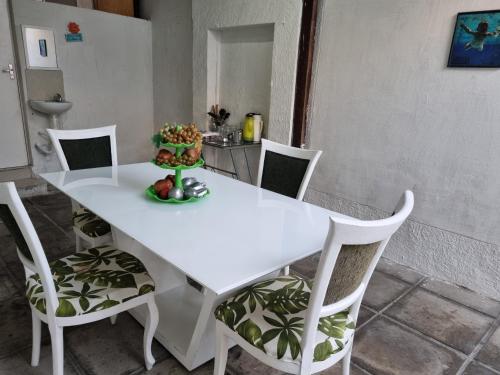 a white table and chairs with a bowl of fruit on it at Casa da Esquina Pousada in Recife