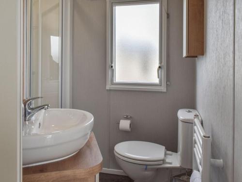 a bathroom with a sink and a toilet and a window at Sea View Lodge in Heysham