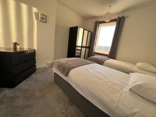 a bedroom with two beds and a dresser and a window at Lomond View Apartment in Ladybank