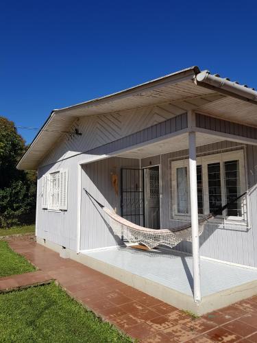 a white house with a hammock on the porch at CASA FULL CENTRAL, 130m quadr, 9 Pessoas, Wi-Fi, 3 Qtos, Churrasqueira Interna, Cozinha-Sala Integrados, 2 Banheiros, Varanda, Jardim, Garagem Coberta 1 Carro, Estac Inter 3 Carros, Lareira de Alta Performance, Fogão de Ferro, Área nos Fundos in Cambará