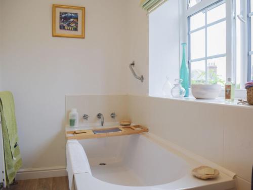 a white bath tub in a bathroom with a window at Stable Cottage in Much Birch