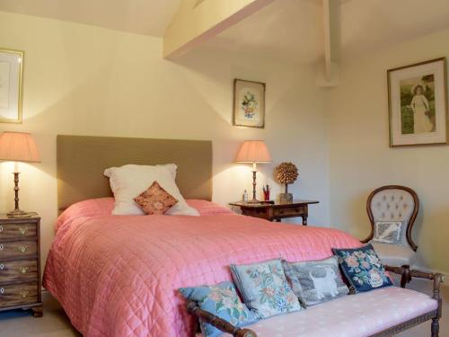 a bedroom with a large bed with a pink bedspread at Stable Cottage in Much Birch