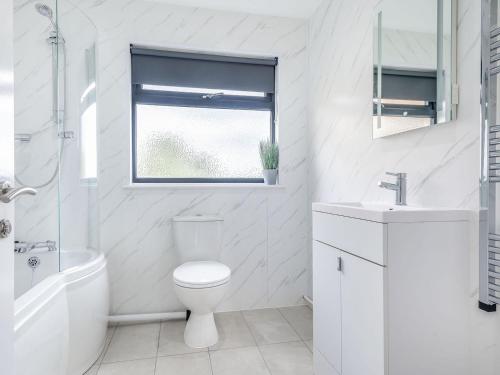 a white bathroom with a toilet and a sink and a window at Oak Tree Lodge - Uk38383 in Lyonshall