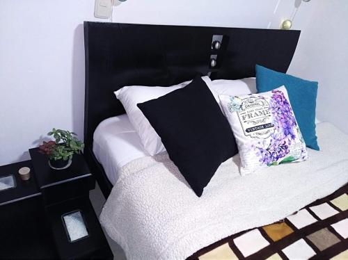 Una cama blanca y negra con almohadas. en HABITACION EN SUBA, en Bogotá