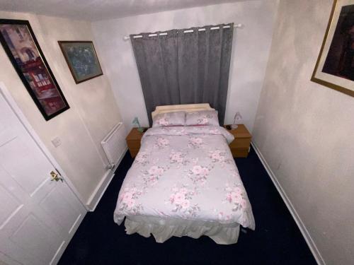 a small bedroom with a bed with pink sheets at Private Lounge and Double Room in Kilwinning