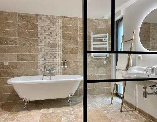 a bathroom with a tub and a sink at Madame Imagine, Lodges & SPA Epinal in Épinal