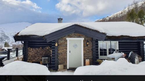 a small log cabin with snow on the roof at Ringstadsætra på sitt aller beste in Stranda