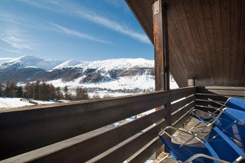a blue chair on a porch with a view of mountains at Alpen Resort Bivio in Livigno