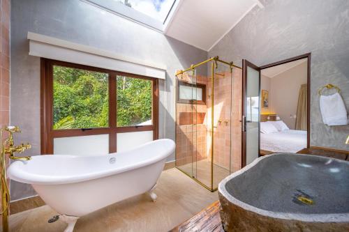 a bathroom with a large tub and a bedroom at Øko Villa in Juquei