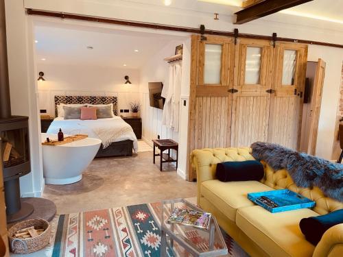 a bedroom with a bed and a couch and a tub at Luxury Barn with Hot Tub, Spa Treatments, Private Dining in Little Budworth