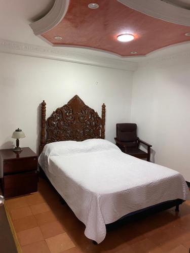 a bedroom with a large bed and a chair at La Casona Hostal in Pereira