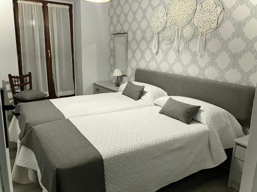 two beds in a bedroom with white and gray walls at CASA AYARAN in Baeza