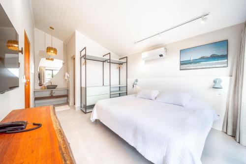 a white bedroom with a bed and a table at Øko Villa in Juquei