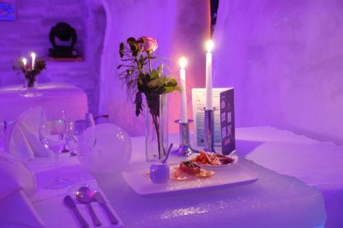 a table with candles and flowers in a purple room at Hotel of Ice Transylvania in Cîrţişoara