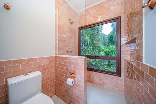 a bathroom with a toilet and a window at Øko Villa in Juquei