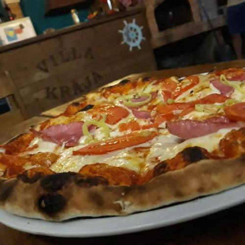 a pizza sitting on a plate on a table at Apartments Kraja in Velipojë