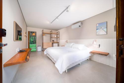 a bedroom with a white bed and a wooden bench at Øko Villa in Juquei