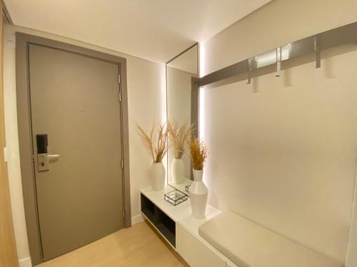 a bathroom with a mirror and vases on a shelf at Luxuoso Studio Setor Marista - 454 in Goiânia