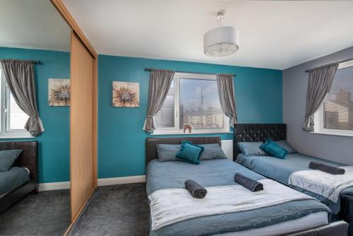 2 camas en una habitación con paredes y ventanas azules en Spacious town house free parking and Wi-Fi, en Thornaby on Tees
