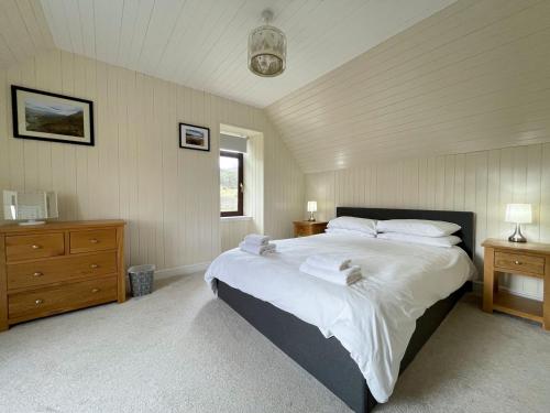 a bedroom with a large bed with white sheets and pillows at Rhianchaitel House in Bettyhill