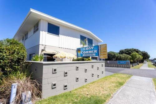 a white building with a sign in front of it at Cosy Corner Holiday Park in Mount Maunganui