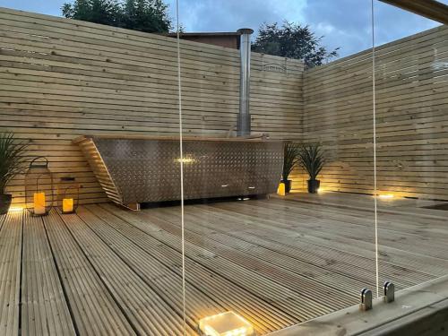 a wooden deck with a bench on a wall at Hill Garth Cottage - Luxury 2 Bed with Wood Burning Hot Tub in Wooler