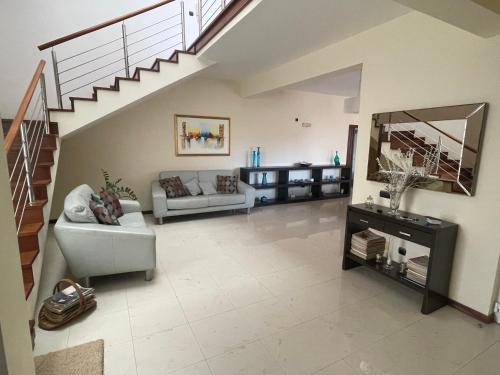 a living room with a couch and a staircase at Villa164 - Luxo, Piscina e Ginásio à beira-mar in Santa Maria