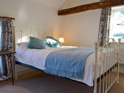 a bedroom with a white bed with blue blankets and pillows at Cranberry Cottage in South Creake