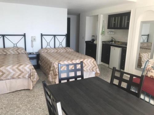 a hotel room with two beds and a table at Suite frente al mar en Torres Gemelas Acapulco in Acapulco