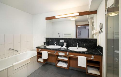 a bathroom with two sinks and a large mirror at KUHOTEL by Rilano in Waidring