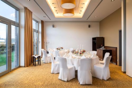 a conference room with white tables and chairs and windows at elaya hotel hamburg finkenwerder in Hamburg