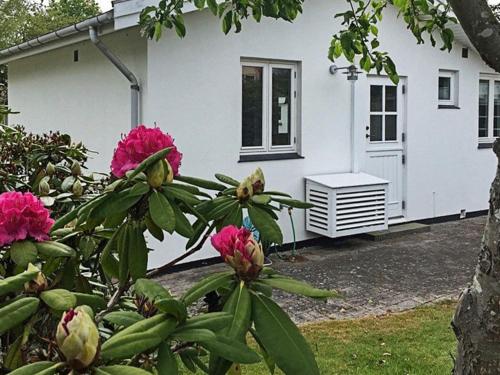 une maison blanche avec des fleurs roses devant elle dans l'établissement 4 person holiday home in Dronningm lle, à Dronningmølle