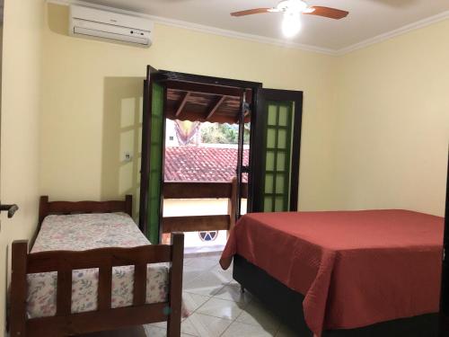 a bedroom with two beds and a door to a balcony at Sobrado 4 dorm Cond. Fechado Praia da Mococa Caraguatatuba in Caraguatatuba