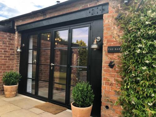 a black sliding glass door on a brick building at Luxury Barn with Hot Tub, Spa Treatments, Private Dining in Little Budworth
