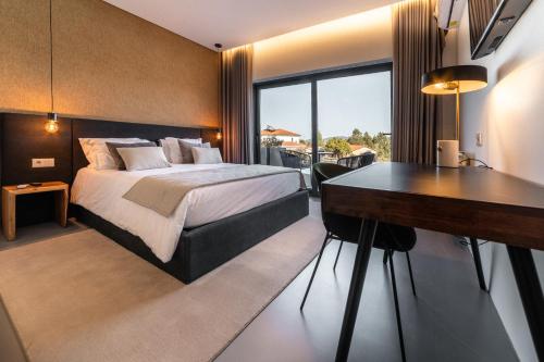 コインブラにあるGranja da Cabritaのベッドとデスクが備わるホテルルームです。