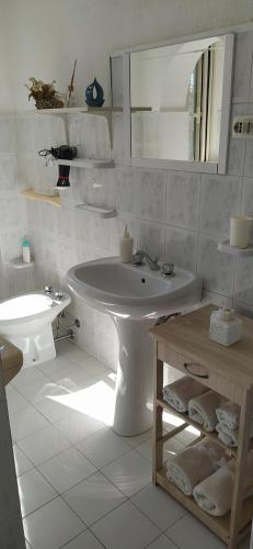 a white bathroom with a sink and a mirror at Appartamento Accanto Al Faro in Vasto