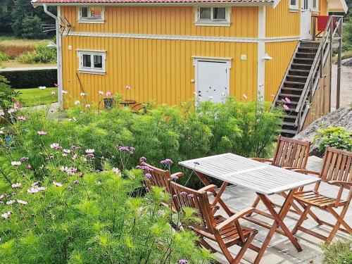 a table and chairs in front of a yellow house at 4 person holiday home in ELL S in Ellos