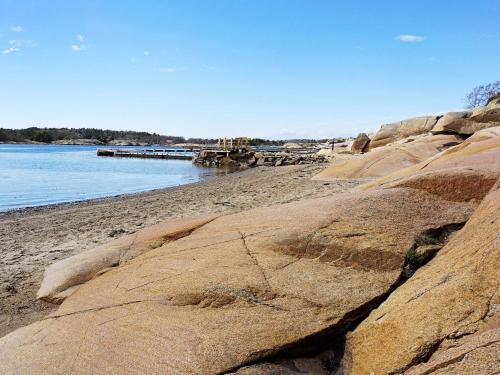 une plage avec de grands rochers et de l'eau et une jetée dans l'établissement 6 person holiday home in STR MSTAD, à Strömstad