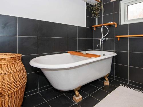 eine weiße Badewanne im Bad mit schwarzen Fliesen in der Unterkunft 6 person holiday home in Ringk bing in Ringkøbing