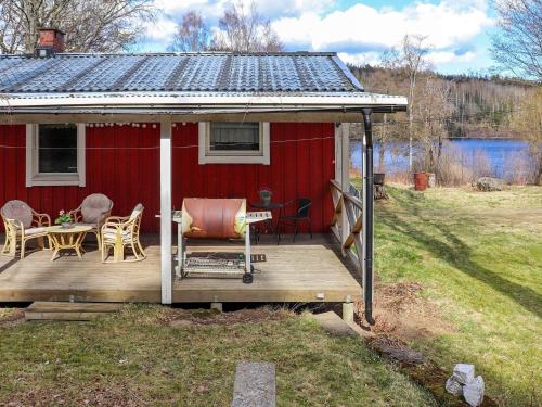 a red house with a deck with a table and chairs at 5 person holiday home in BILLINGFORS in Billingsfors